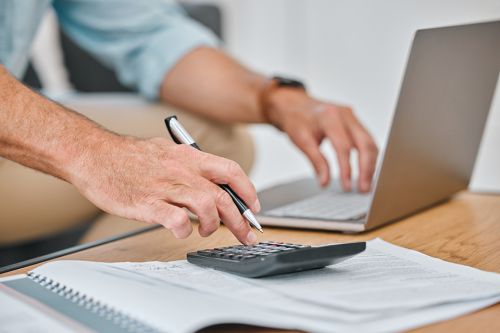 © K Davis/peopleimages.com - Adobe Stock.com Foto: Männerhände auf PC und Taschenrechner